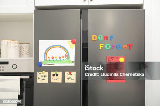 istock Modern refrigerator with child's drawing, notes and magnets in kitchen 1335000291
