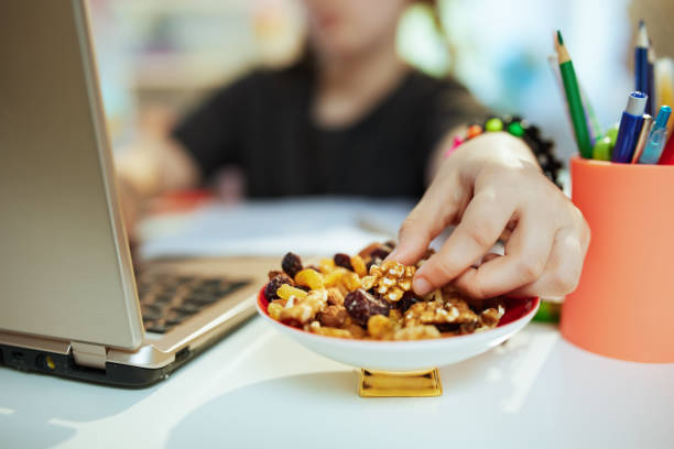 Modern school girl distance learning and eating healthy snack stock photo