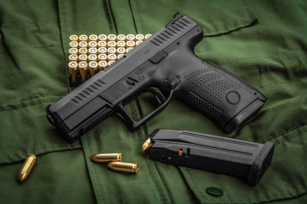 Modern semi-automatic pistol and cartridges for it on a green background. A short-barreled weapon for self-defense. Arming the army and police. stock photo