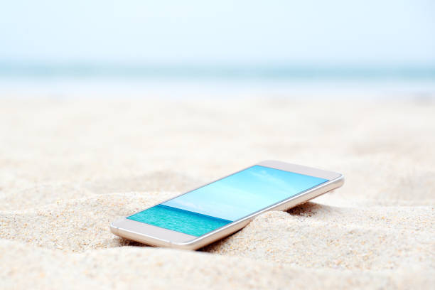 Modern smart phone on the beach with travel photo. Vacation background. stock photo