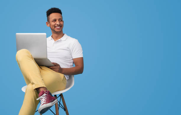 moderne student met behulp van laptop in de buurt lege ruimte - gekleurde achtergrond stockfoto's en -beelden