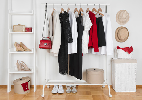 Modern wardrobe interior with different female clothes, hats and shoes