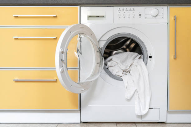 Modern washing machine stands in the kitchen Modern washing machine with fresh and clean laundry towels stands in the kitchen. Concept of house with built in appliance dryer stock pictures, royalty-free photos & images