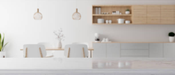 Modern white kitchen countertop with a copy space over blurred modern minimal dining room stock photo
