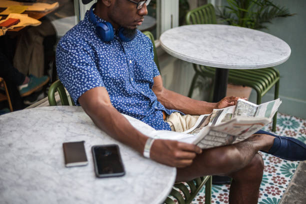 giovane moderno che legge il giornale nella caffetteria in attesa di un caffè - young man read newspaper foto e immagini stock