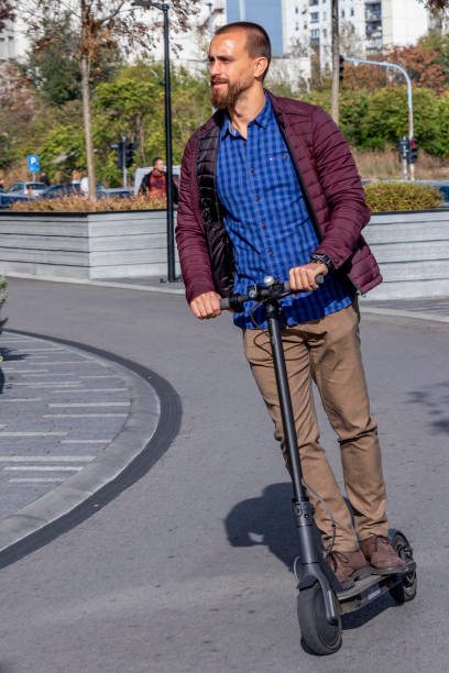 Modern young man riding electric scooter through city stock photo