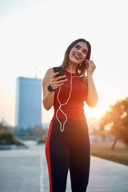 Modern young woman with cellphone making pause during jogging exercise. stock photo