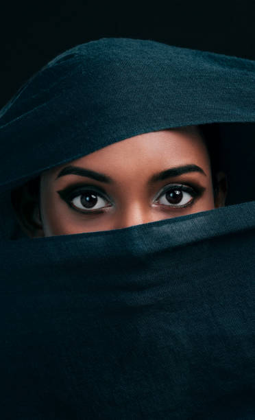 Modesty is the new sexy Cropped shot of an attractive young woman wearing a hijab and only exposing her eyes while against a black background beautiful arab woman stock pictures, royalty-free photos & images