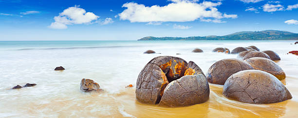 Moeraki boulders in the ocean against a blue sky stock photo