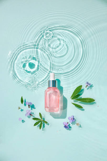 Moisturizing cosmetic products on water with drops. Serum glass bottle and cream jar on aqua surface with waves in sunlight. Concept for advertising organic moisturizing skin care, spa. stock photo