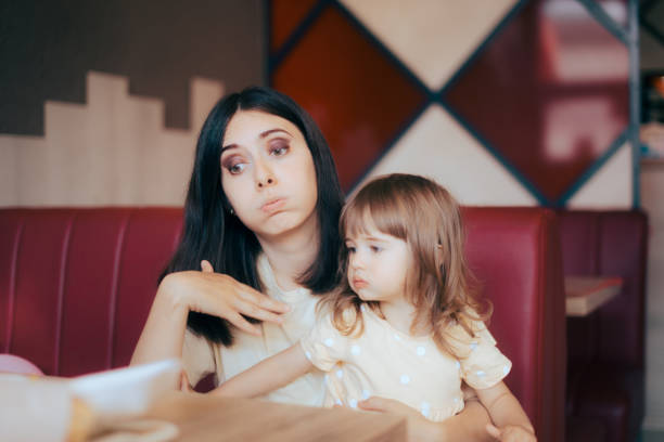 Mom and Child Feeling the Heat Sitting in Indoors Restaurant stock photo