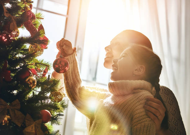 moeder en dochter versier de kerstboom - vrouw kerstboom versieren stockfoto's en -beelden