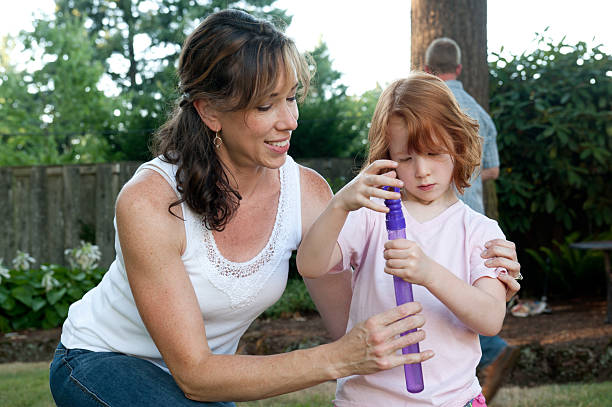 Mom and daughter play with bubbles in backyard. stock photo