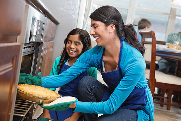 Mom and daughter removing apple pie from oven in kitchen Mom and daughter removing apple pie from oven in kitchen hot latino girl stock pictures, royalty-free photos & images