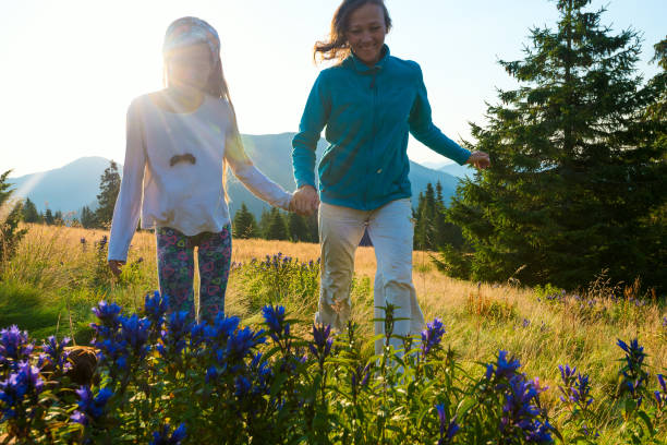 Mom and her teenage daughter are running around in a meadow stock photo