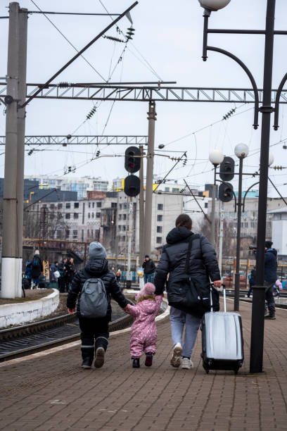 Mom and kids at train station in Lviv, Ukraine Lviv, Ukraine - March 3, 2022: A mother and two children hold hands as they walk down the platform after disembarking a train at the Lviv train station. lviv photos stock pictures, royalty-free photos & images