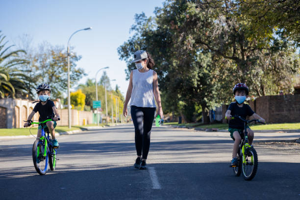 мама уход за своими мальчиками на улице в то время как день езда на велосипеде в пандемии вируса короны - south africa covid стоковые фото и изображения