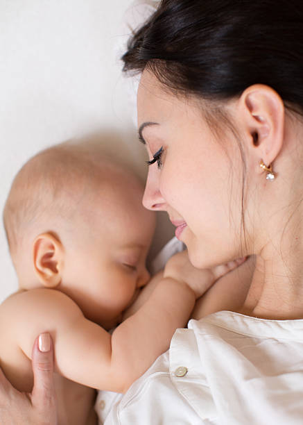Mom feeding breast baby on the bed, top view. stock photo
