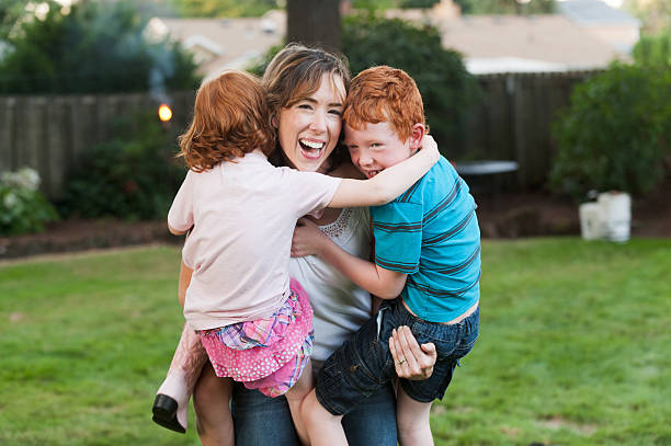 Mom hugs her children in their backyard stock photo