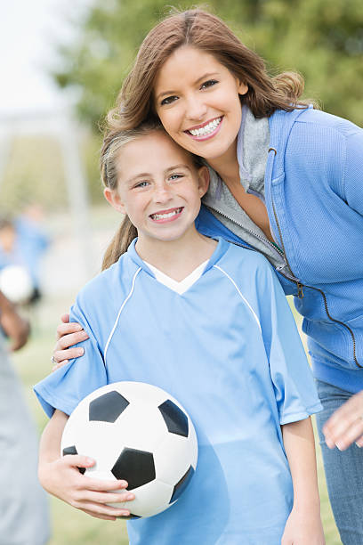 mutter posieren mit tochter am rande fußball-spiel - soccer mom stock-fotos...