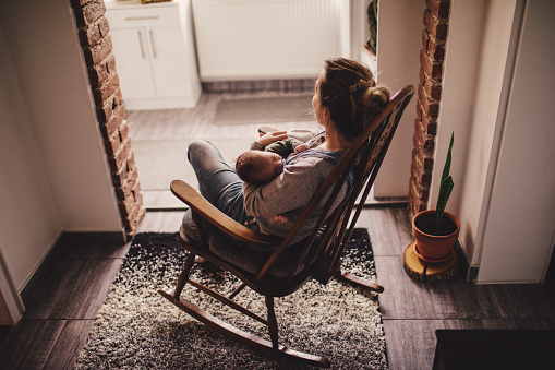 Photo of a young mother holding her newborn baby, while sitting in a rocking chair
