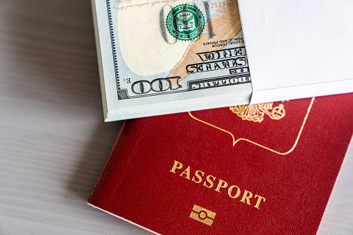 A bundle of US dollars lies on a passport. The concept of buying a passport for cash.