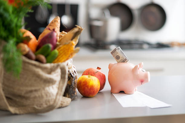 Money in piggy bank and purchases on table. Closeup stock photo