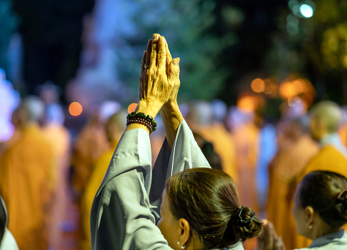 Ho Chi Minh City, Vietnam - December 12th, 2019: Monks and Buddhists are reverently bowing to Buddha during evening ceremony for Amitabha Buddha at an ancient temple in Ho Chi Minh City, Vietnam