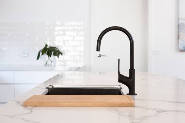 Monochrome kitchen detail of black gooseneck tap Monochrome kitchen detail of black gooseneck tap set in a white marble counter top faucet stock pictures, royalty-free photos & images