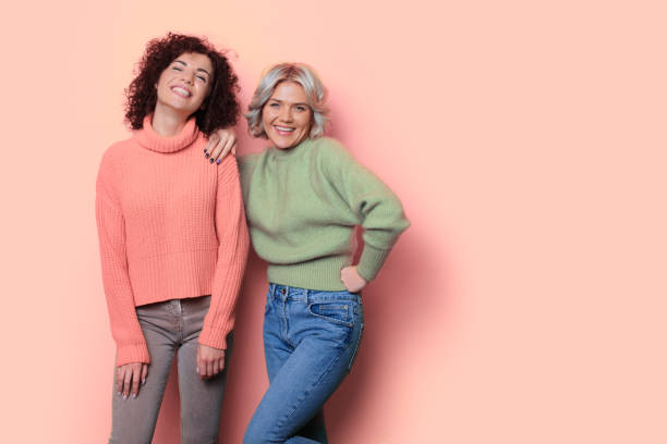 Monochrome photo of two women with curly hair posing on a studio wall with free space smiling at camera stock photo