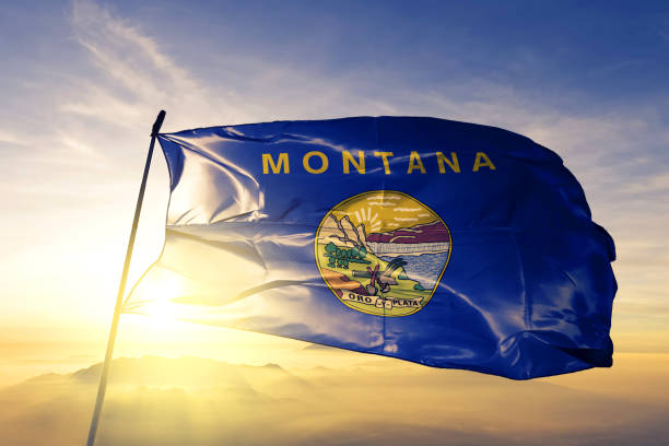 Montana state of United States flag textile cloth fabric waving on the top sunrise mist fog stock photo