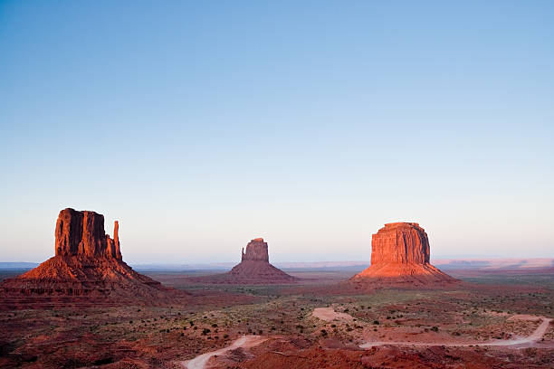 The Mittens and Merrick Butte at Sunset Monument Valley is on the Arizona/Utah border near Oljato, Utah, USA. The valley with its strange sandstone formations is the epitome of the Old West. This iconic view was taken at sunset, capturing the other-worldly glow on the red rock. jeff goulden monument valley stock pictures, royalty-free photos & images