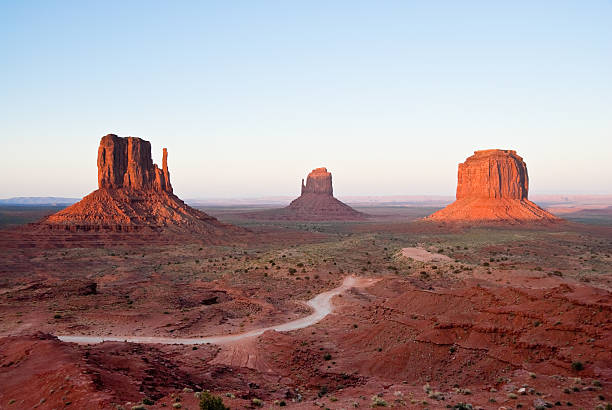 The Mittens and Merrick Butte at Sunset Monument Valley is on the Arizona/Utah border near Oljato, Utah, USA. The valley with its strange sandstone formations is the epitome of the Old West. This iconic view was taken at sunset, capturing the other-worldly glow on the red rock. jeff goulden monument valley stock pictures, royalty-free photos & images