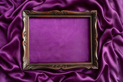 moody mockup photography, of an old sculpted wooden frame, on purple satin background, wallpaper design