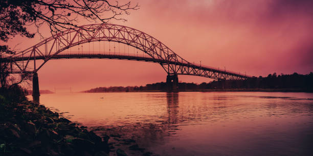 Moody seascape with dramatic stormy clouds over the Bourne Bridge on Cape Cod Canal at sunset stock photo