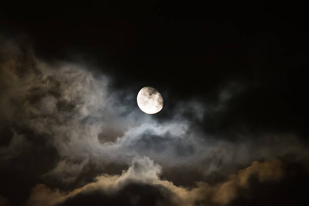 moon surrounded by dark clouds at night full moon surrounded by dark clouds at night full moon clouds stock pictures, royalty-free photos & images