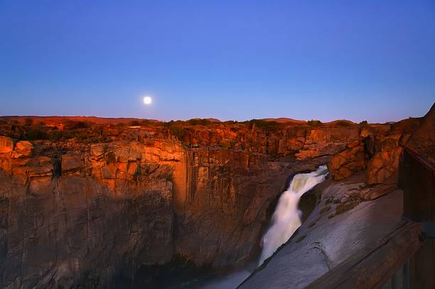 Moonrise Over Augrabies Falls A full moon rises at sundown and the residual sunlight is illuminating the fall wall of the Augrabies Falls on the Orange River as well as obscuring  any stars. I think this is a pretty iconic image of this amazing national park in the Northern Cape province of South Africa augrabies falls national park stock pictures, royalty-free photos & images