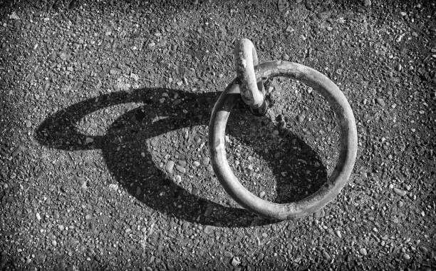 Mooring ring along the quay in the harbor High angle view of a mooring ring projecting its shadow on a sunny day along the quay. anchor point stock pictures, royalty-free photos & images