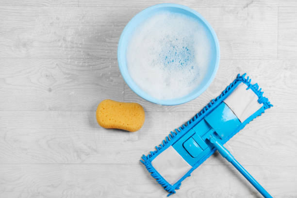 Mopping, blue wet microfiber mop with detergent. Cleaning disinfection kit on a white floor isolated. Housekeeping concept stock photo
