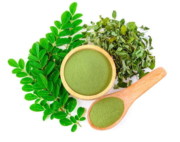 Moringa powder in wooden bowl with  fresh Moringa and dried leaves  on white background,Top view. stock photo