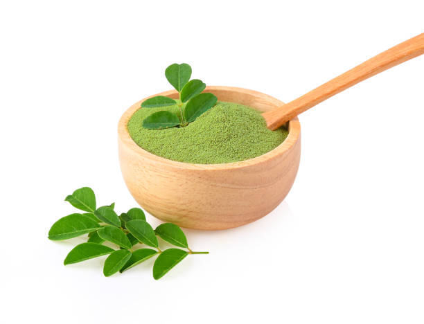 Moringa powder in wooden bowl with  fresh Moringa  leaves  on white background stock photo