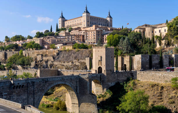 Morning at Toledo - Panoramic morning view of the historic city Toledo at Puente de Alcántara, a Roman arch bridge at front of east city gate Puerta de Alcántara and crossing over Tagus River. Toledo, Spain. stock photo