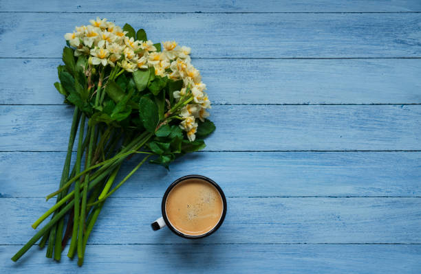 Morning cup of coffee and spring daffodil flowers on blue rustic background. stock photo