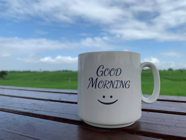 morning greeting with happy smile on a coffee or tea cup with blue sky over the rural paddy field view. - happy friday emoticon stockfoto's en -beelden