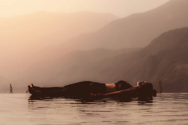 Photo of Morning light with Beautiful Attractive Asian woman practice yoga Dead Body or Savasana on the pool above the Mountain peak in front of beautiful nature views in SAPA vietnam,so comfortable,Warm Tone