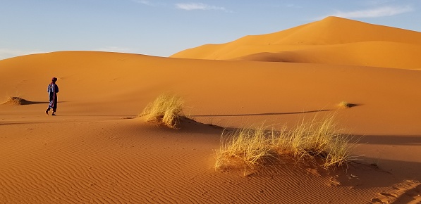 Moroccan man walks through the Sahara Desert