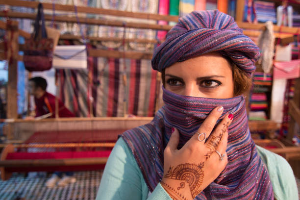 Moroccan woman with silk scarf covering her face in Morocco with looms in the background stock photo
