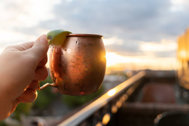 A moscow mule held up at a rooftop restaurant bar at sunset stock photo
