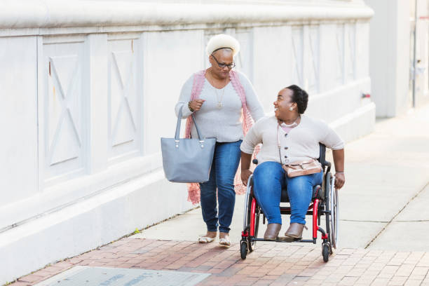 mother, adult daughter with spina bifida, in city - wheelchair street happy imagens e fotografias de stock