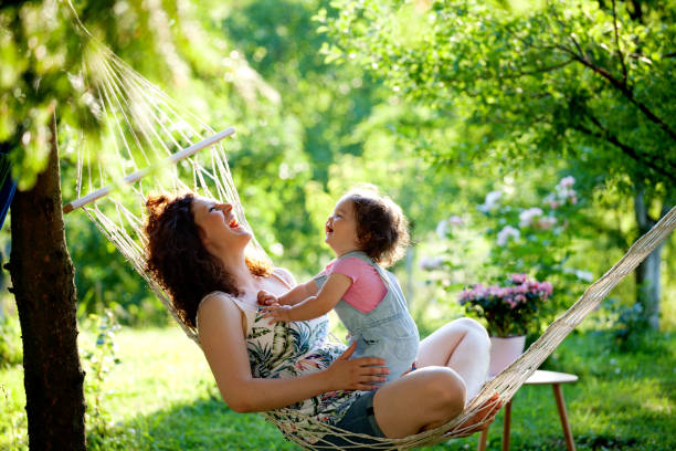Mother and baby girl in hammock laughing and playing stock photo